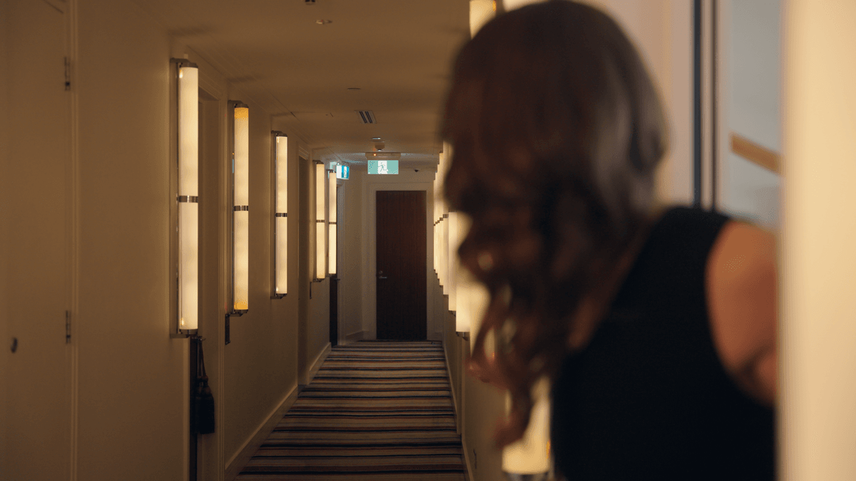 A figure looking down a quiet hotel corridor
